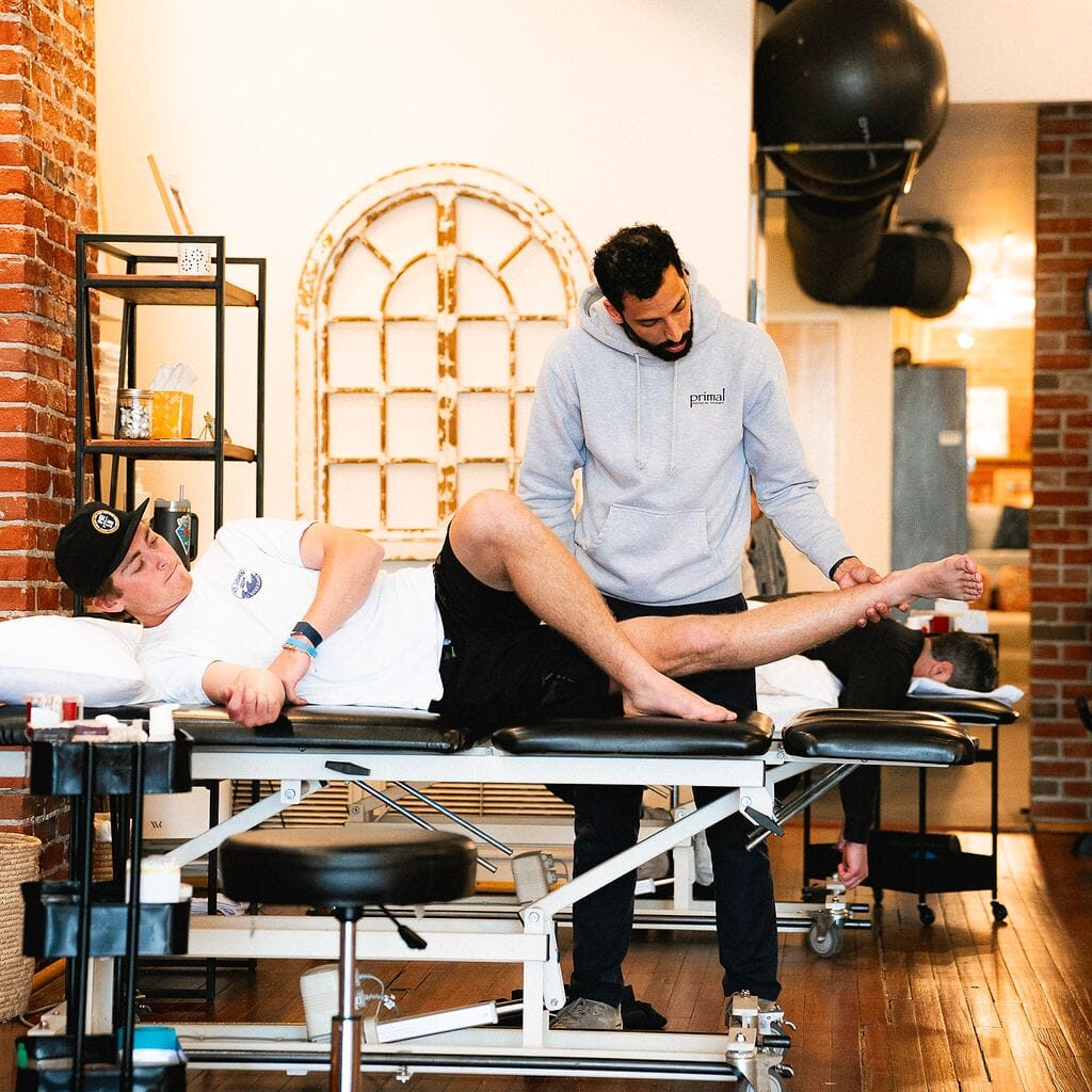 Physical therapist examining a patient's knee for signs of swelling, instability, or sports injury.